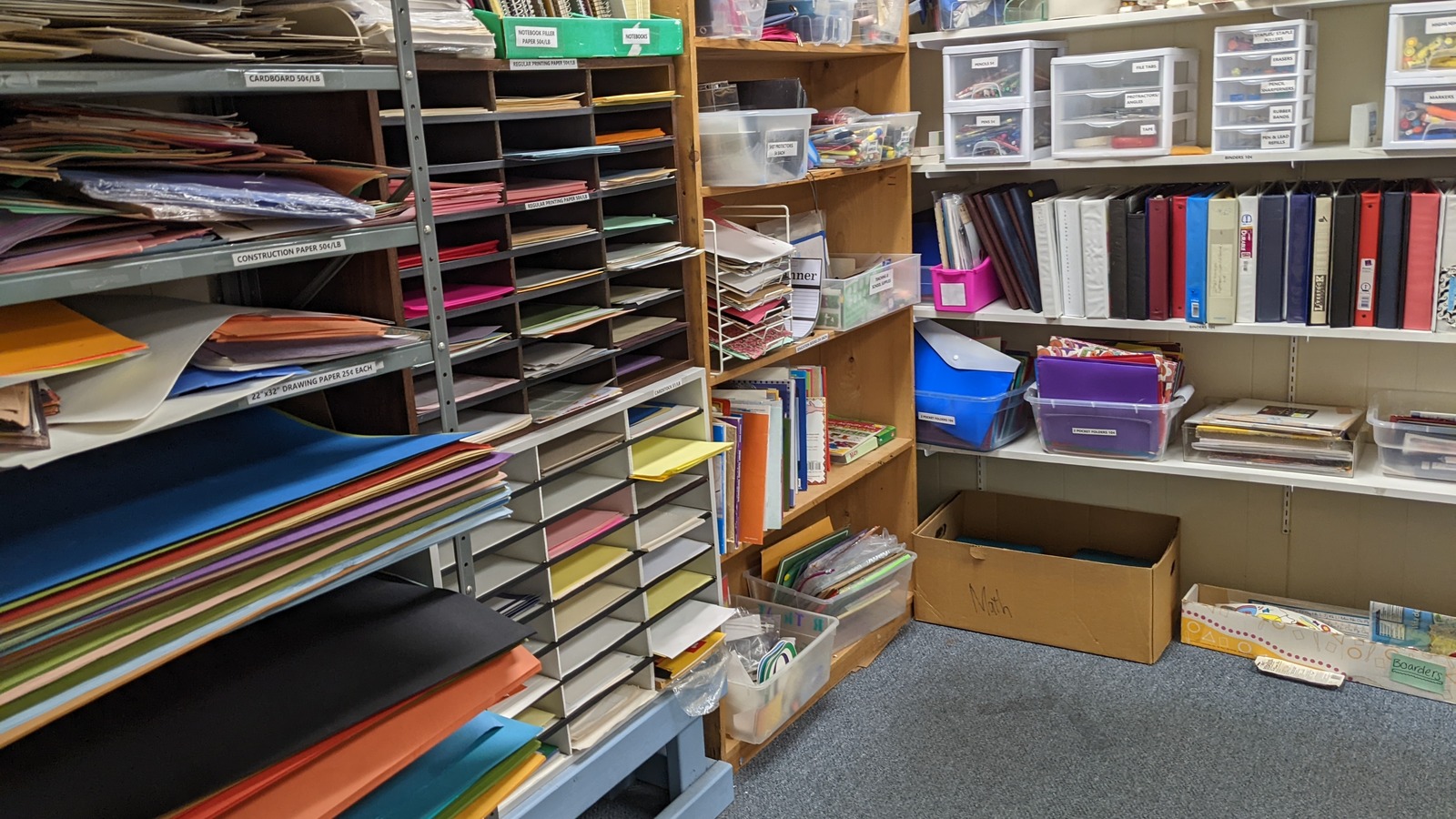 Colorful paper racks, binders, and sorted classroom materials at Lancaster Creative Reuse.