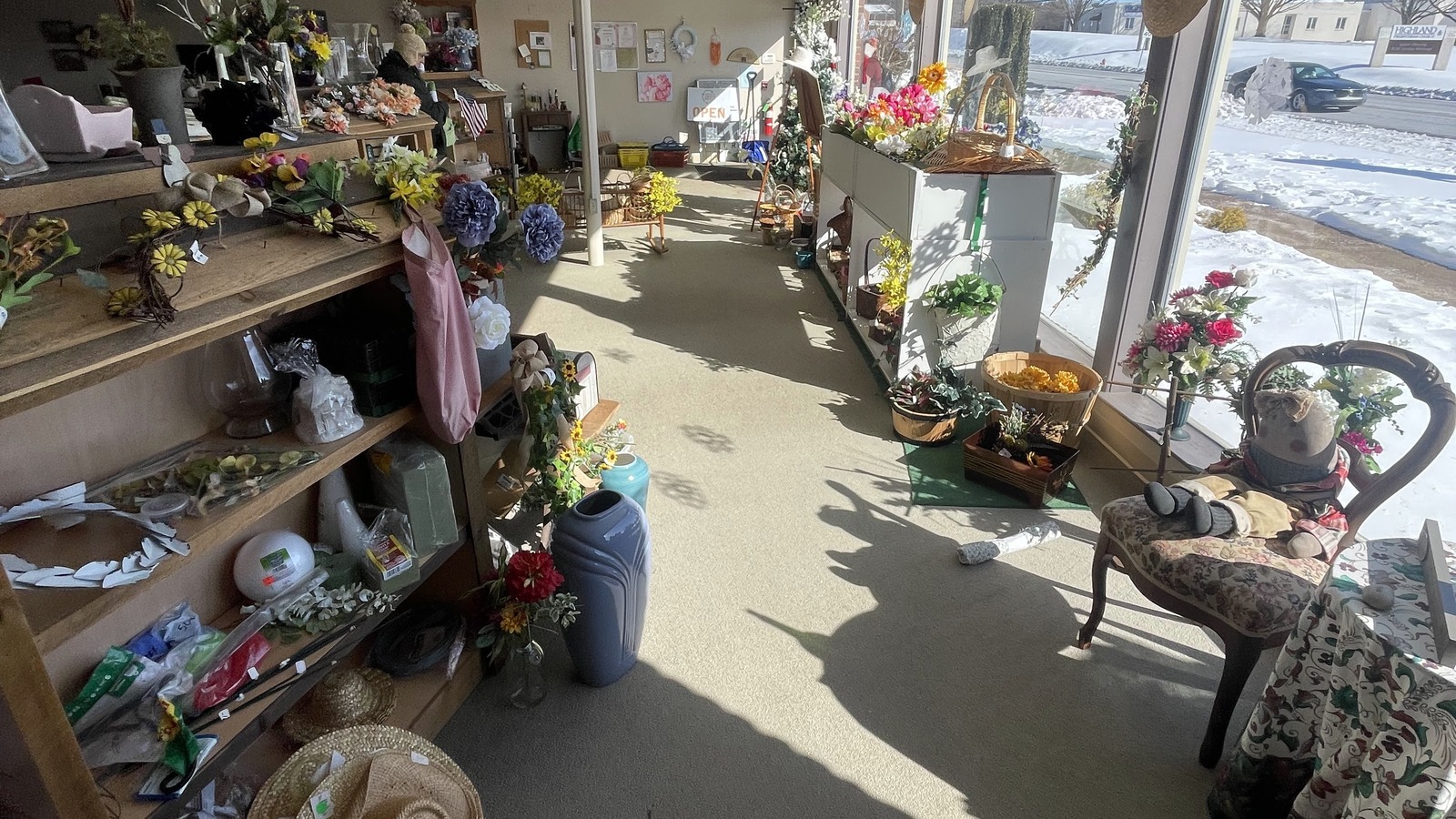 Sunlit front room with florals, baskets, and display shelves at Lancaster Creative Reuse.
