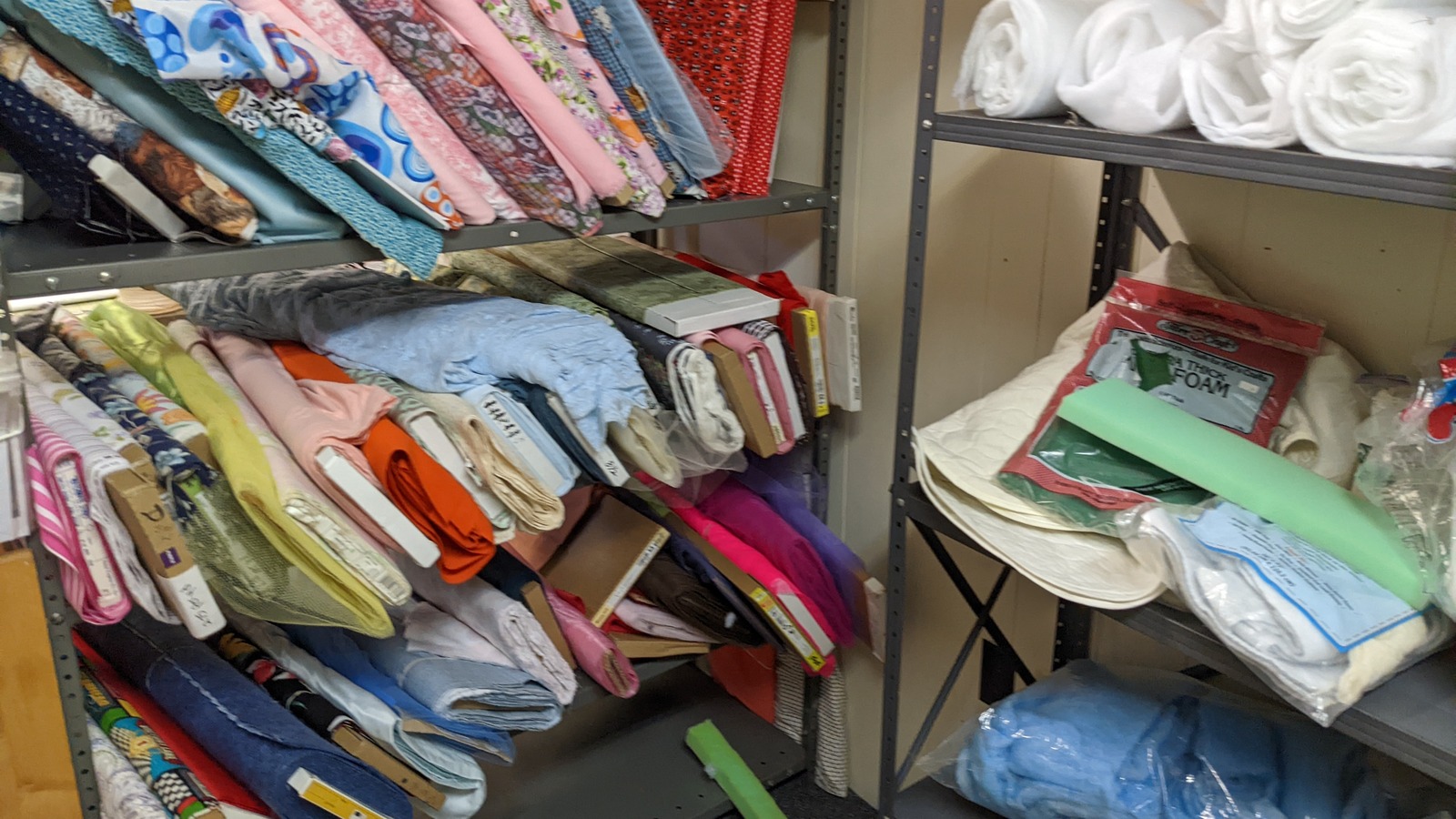 Fabric aisle beside embroidery hoops and sewing supplies at Lancaster Creative Reuse.