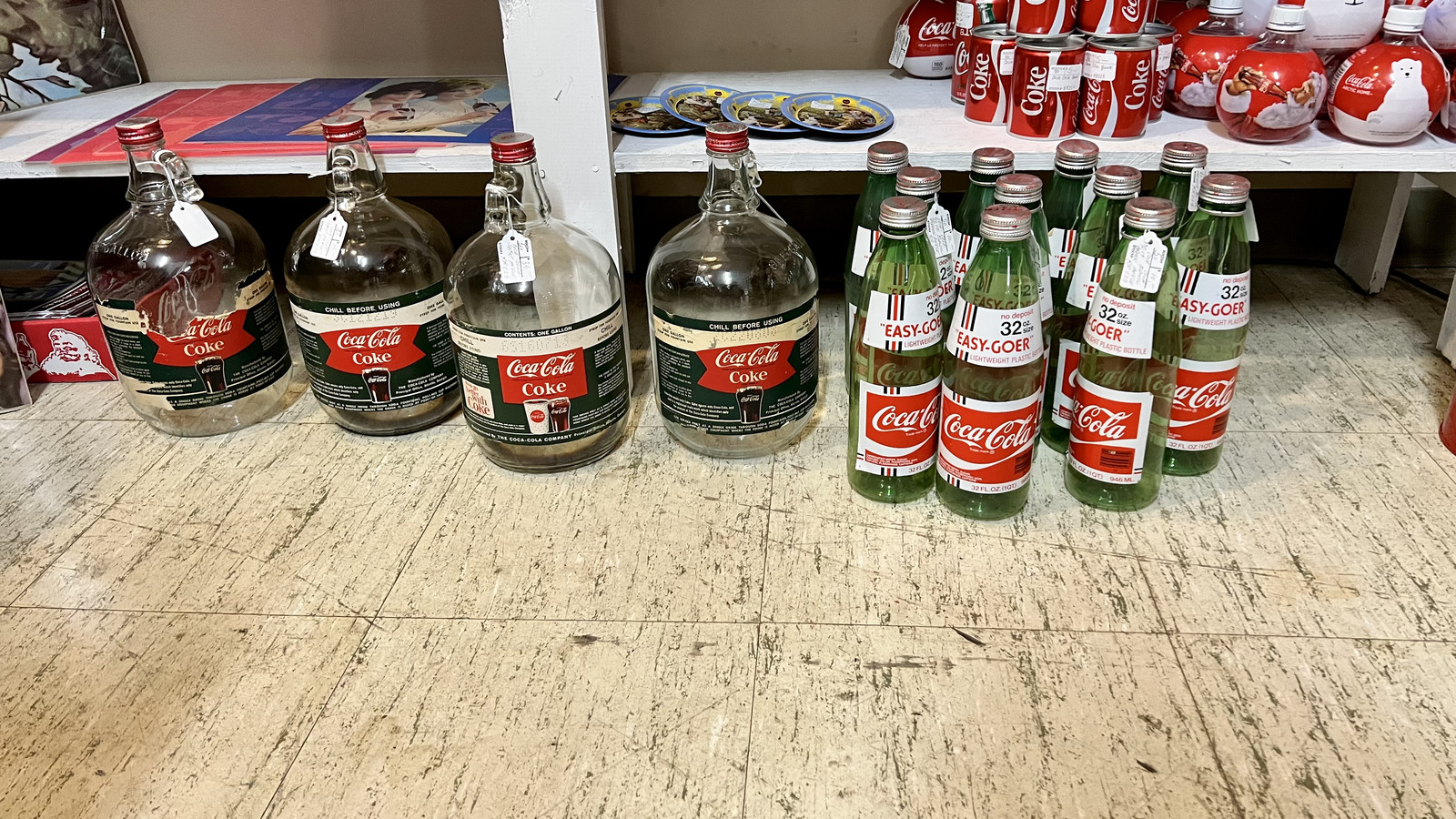 Vintage Coca-Cola bottles and glass jugs lined up on a floor display at Markle Exit 286 Antique Mall