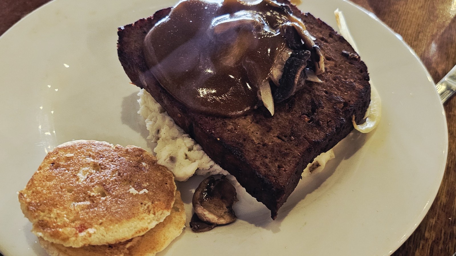 Thick meatloaf slice with brown gravy, mashed potatoes, and a biscuit at Puckett's Restaurant