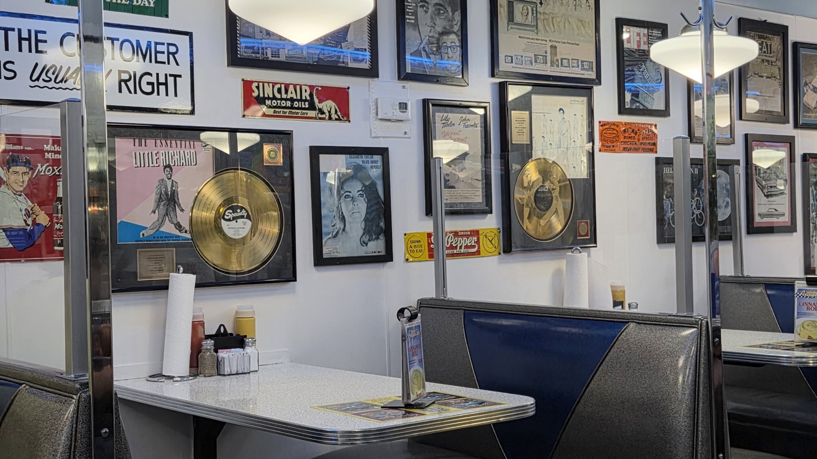Blue booth seating and framed record wall inside Mel's Classic Diner