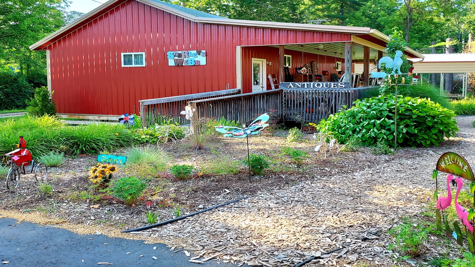 Red outbuilding with antique sign, porch, and garden path behind Brown County Antique Mall