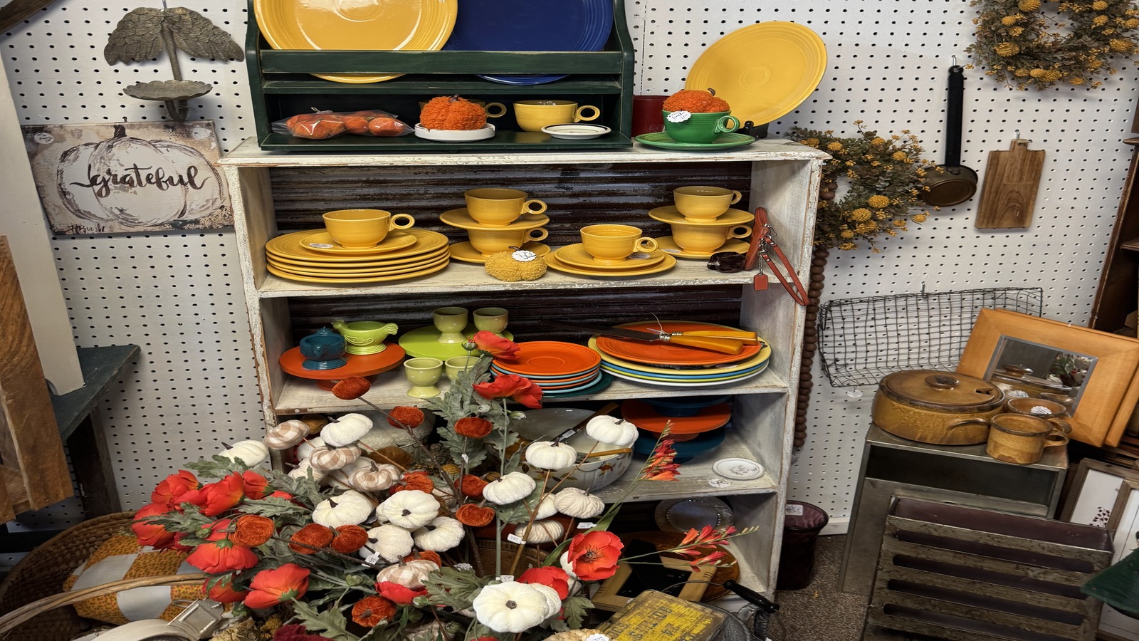 Colorful vintage plates, cups, wreaths, and autumn decor arranged on shelves at Brown County Antique Mall