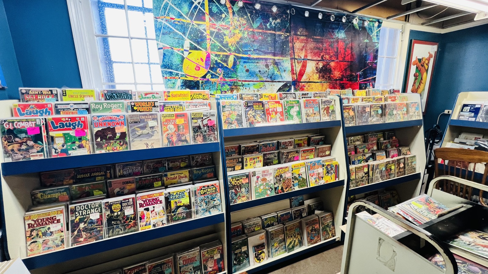 Shelves of vintage comic books beneath bright artwork at Midland Arts & Antiques Market in Indianapolis