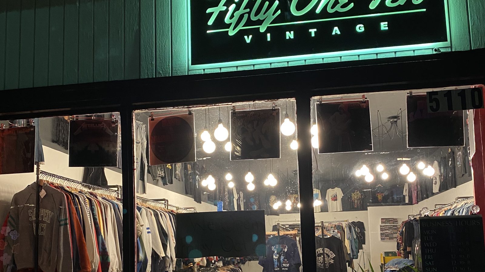 Mirror-lined front room with clothing racks and hanging lights inside Fifty One Ten Vintage in Pittsburgh.