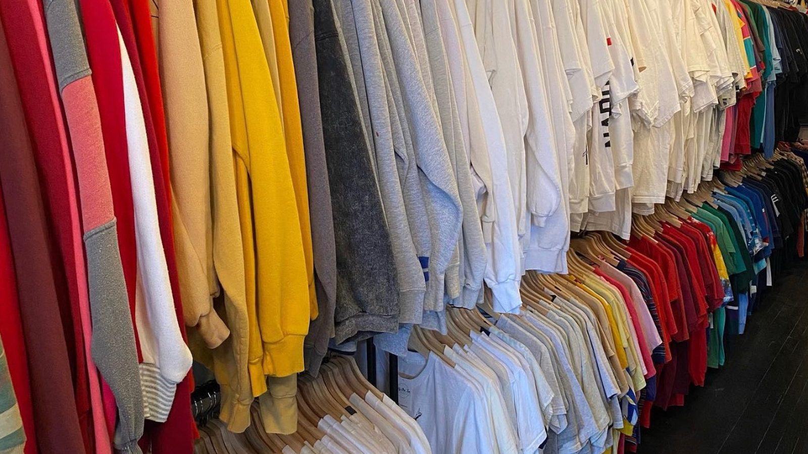 Color-sorted vintage tops hanging in a bright rack at Fifty One Ten Vintage in Pittsburgh.