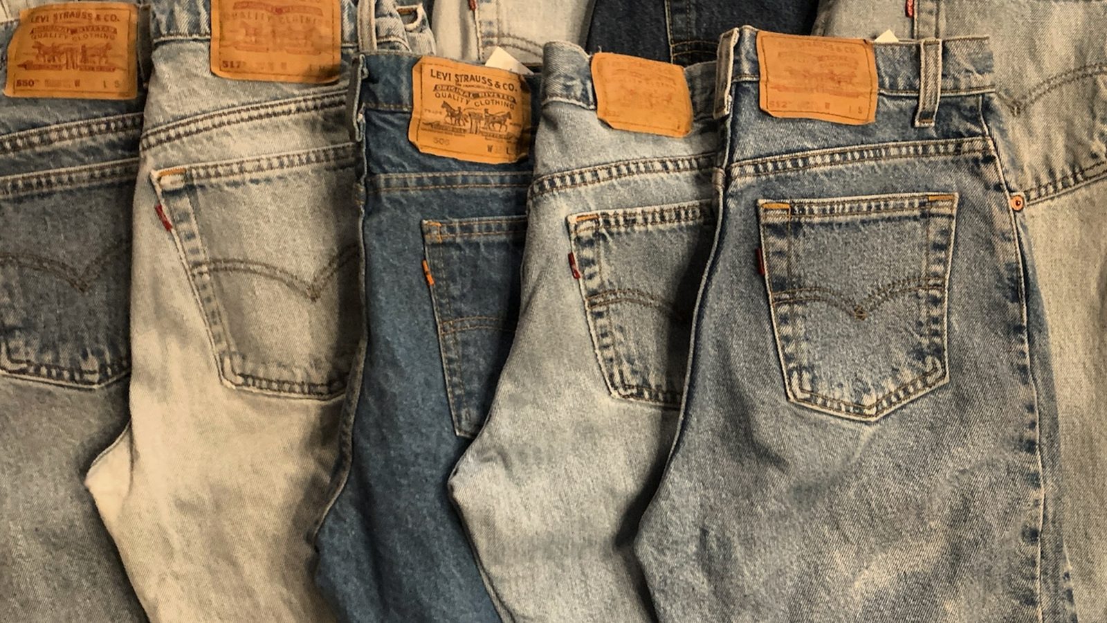 Faded denim jeans hanging in a tightly packed wall display at Fifty One Ten Vintage in Pittsburgh.