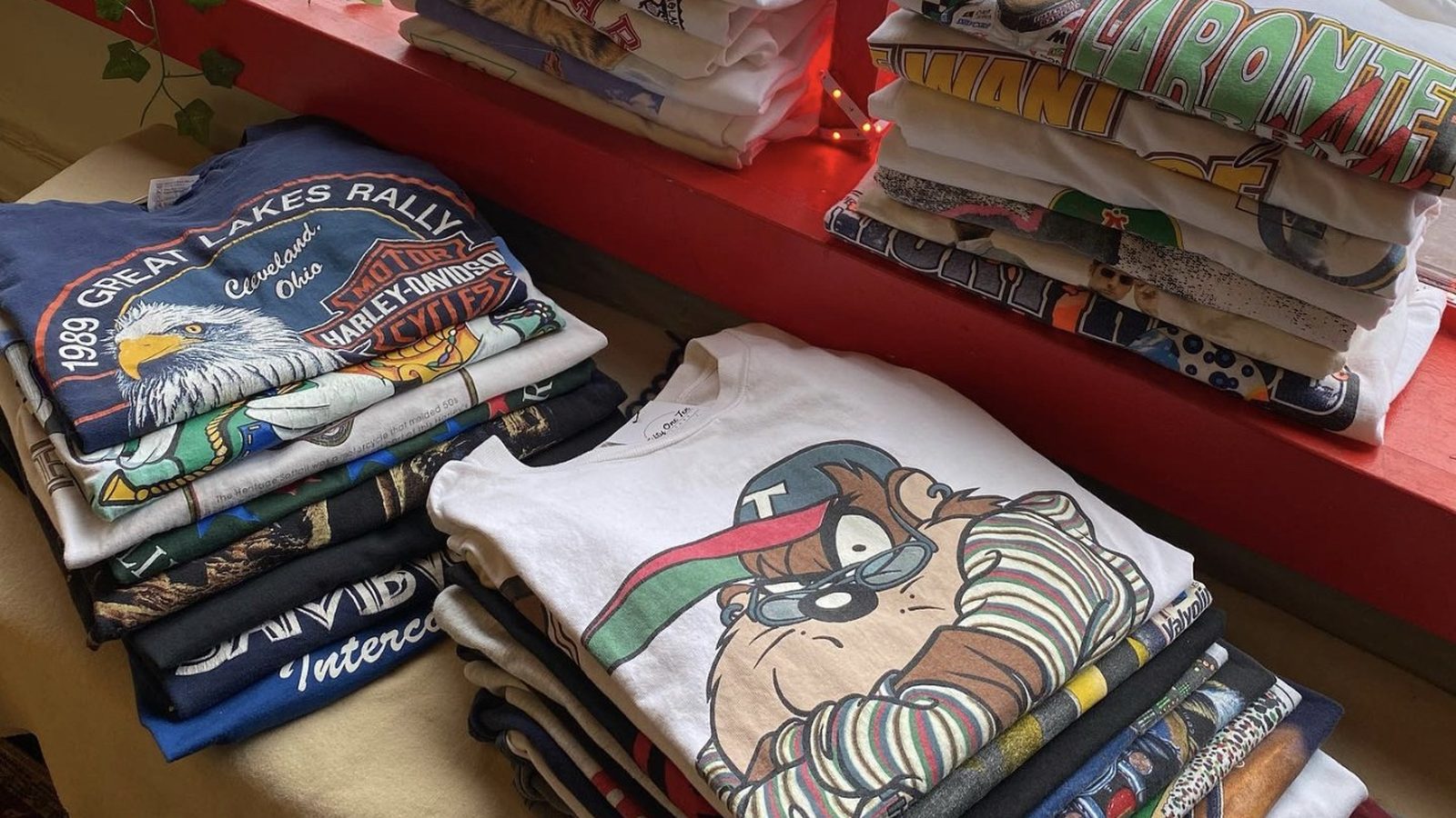 Folded graphic tees displayed on a red counter at Fifty One Ten Vintage in Pittsburgh.