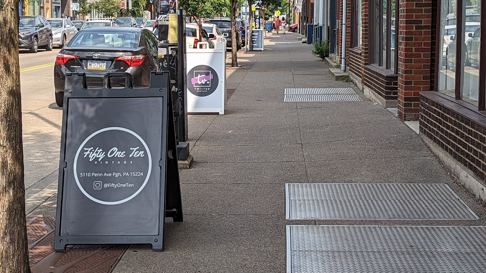 Penn Avenue sidewalk sign and storefront view outside Fifty One Ten Vintage in Pittsburgh.
