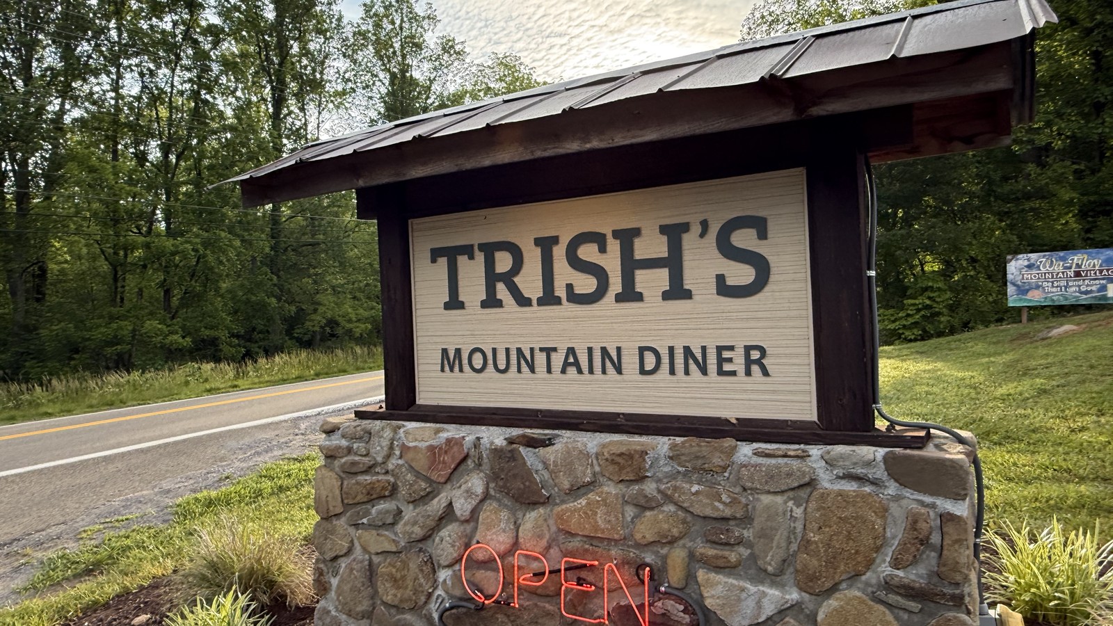Stone roadside sign for Trish's Mountain Diner beside East Parkway in Gatlinburg