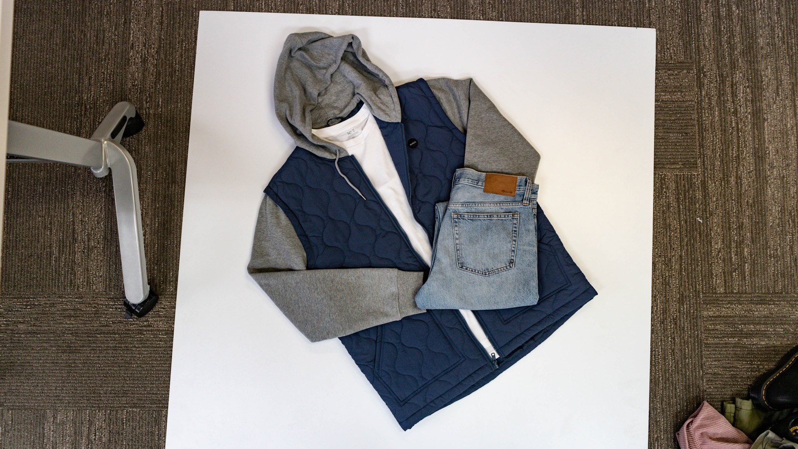 Layered vest, hoodie, and denim display arranged on a white presentation table at Uptown Cheapskate West York.