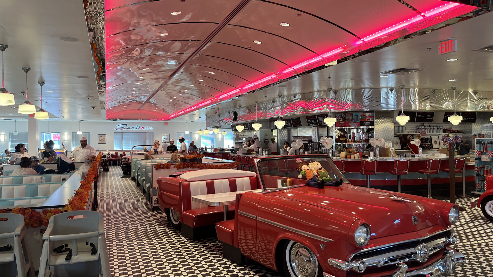 Red neon ceiling lines above booths and counter seating at Sunliner Diner