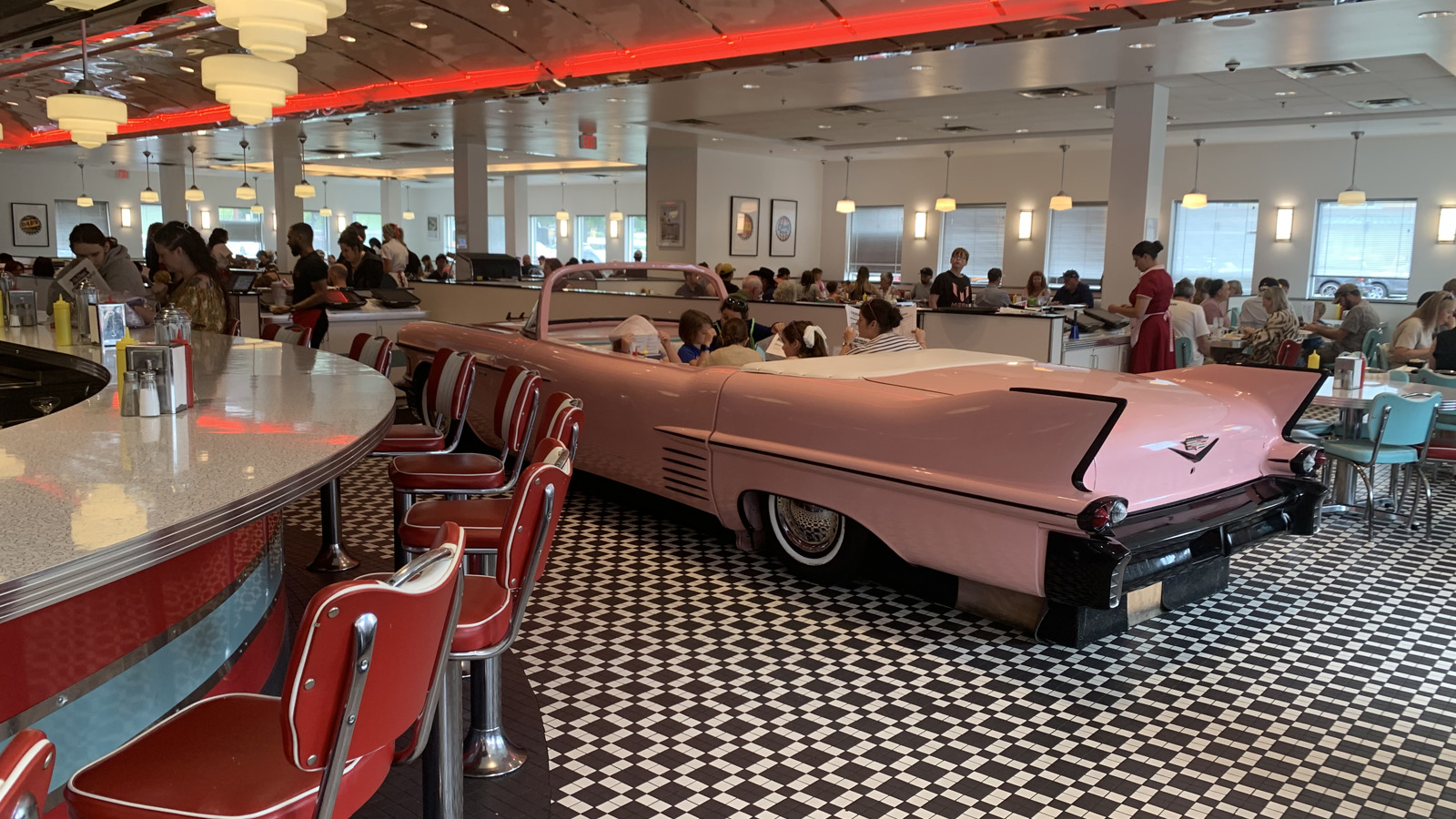 Pink Cadillac tailfins beside counter stools at Sunliner Diner