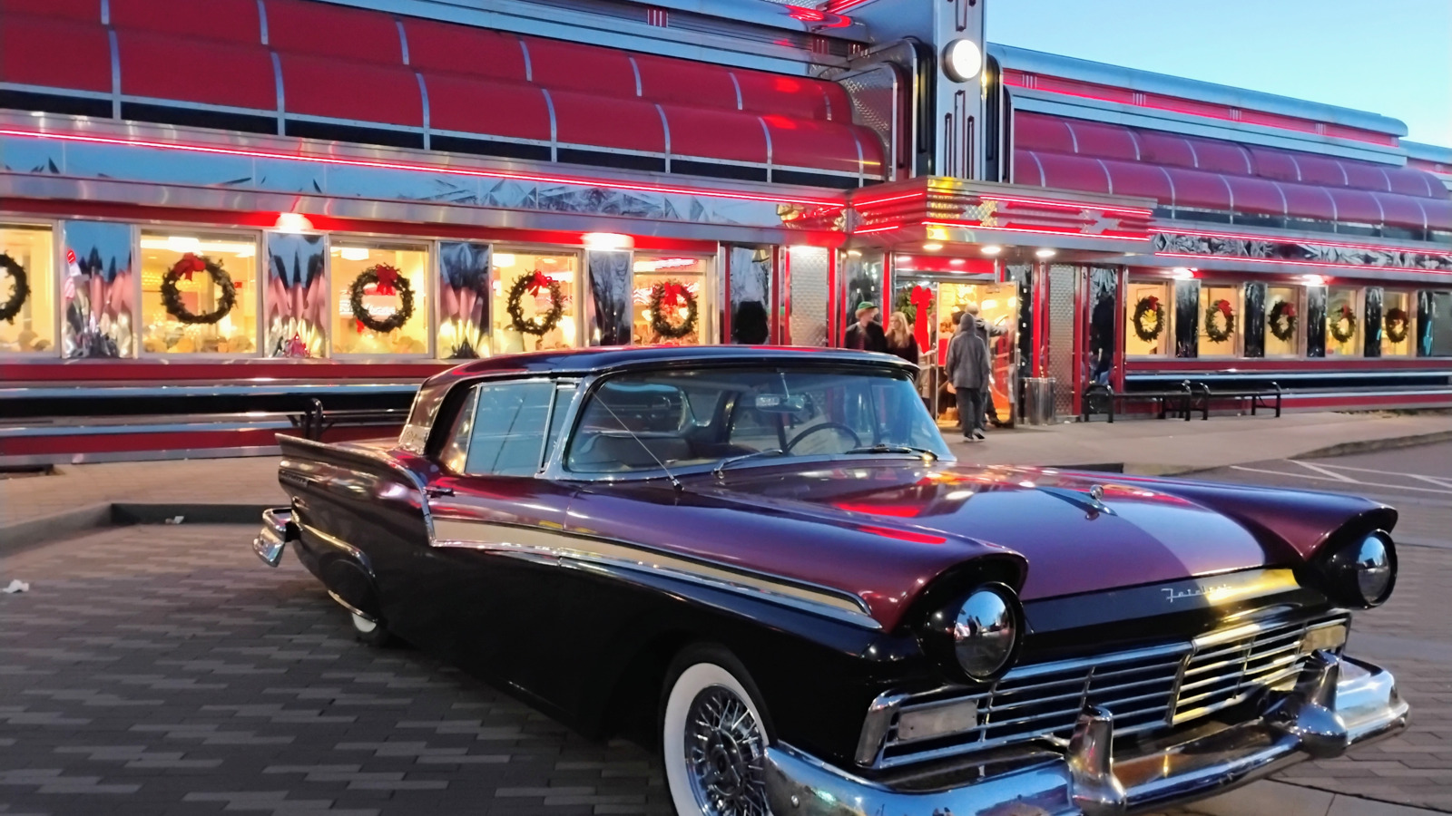 Vintage car parked under the red neon exterior at Sunliner Diner