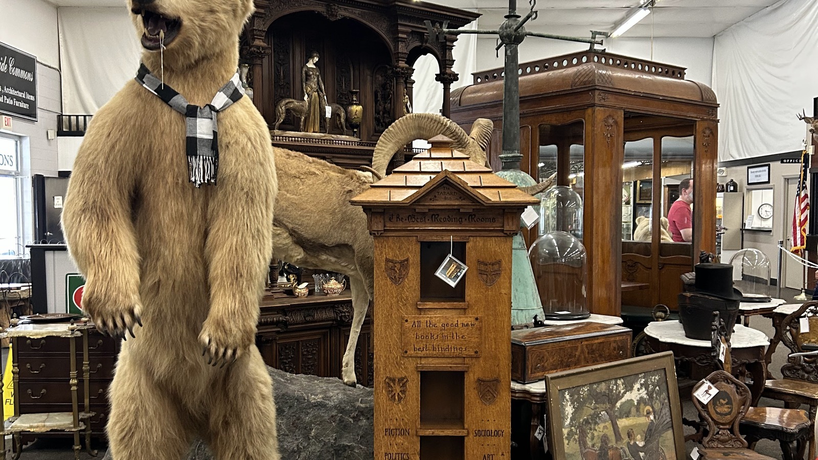 Lodge-style display with a taxidermy bear, carved wood, and large antique furniture