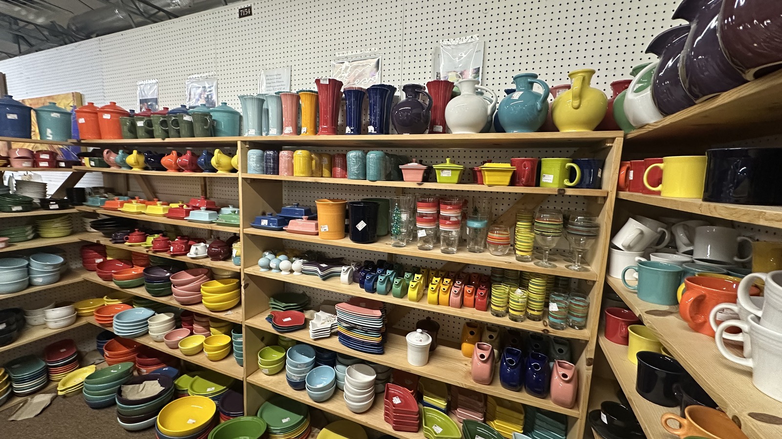 Shelves packed with bright pottery, pitchers, casserole dishes, and colorful tableware