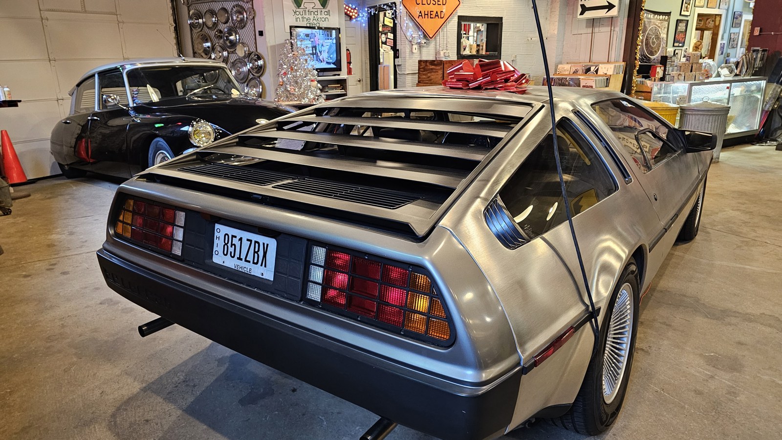 Stainless DeLorean parked among records, hubcaps, and hanging road signs at The Bomb Shelter