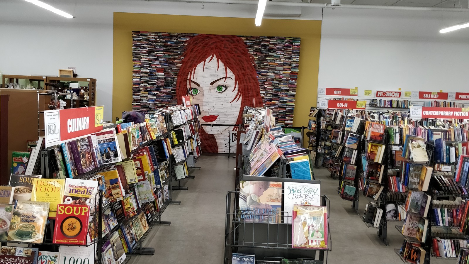 Used book aisles leading toward a large mural inside Antiques Village in Dayton