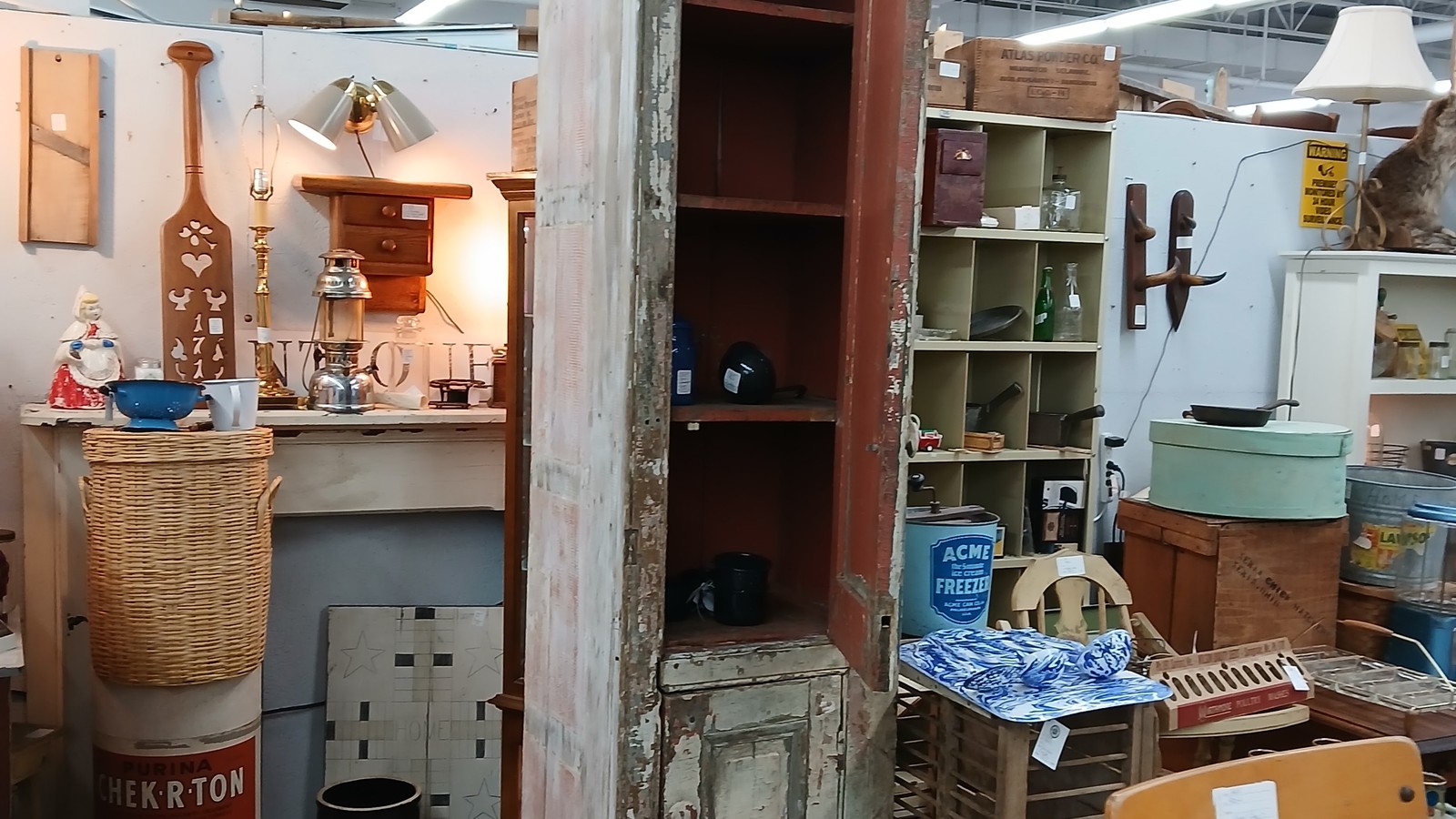 Tall reclaimed cabinet surrounded by vintage furniture and mixed decor inside Antiques Village
