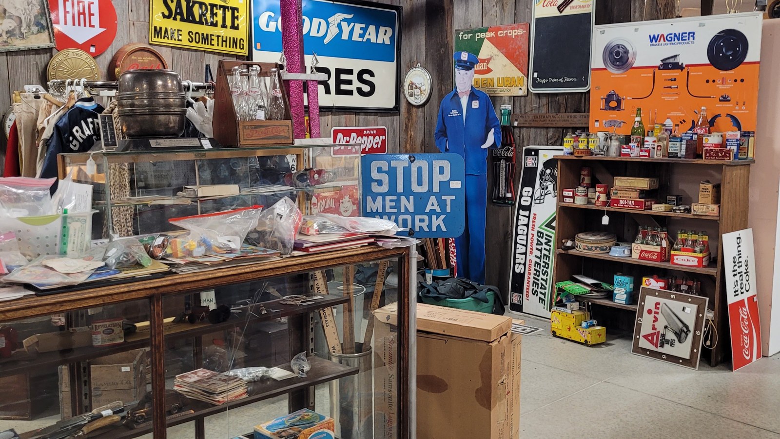 Vintage road signs, bottles, and display cases inside a memorabilia-heavy booth at Jeffrey's Antique Gallery