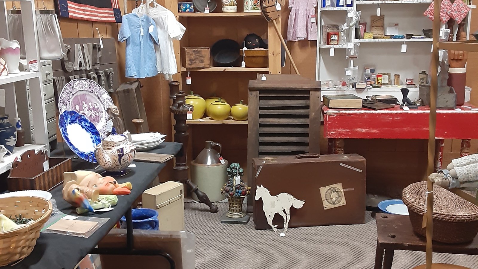 Rustic booth with painted table, pottery, vintage signs, and small household antiques at Jeffrey's Antique Gallery