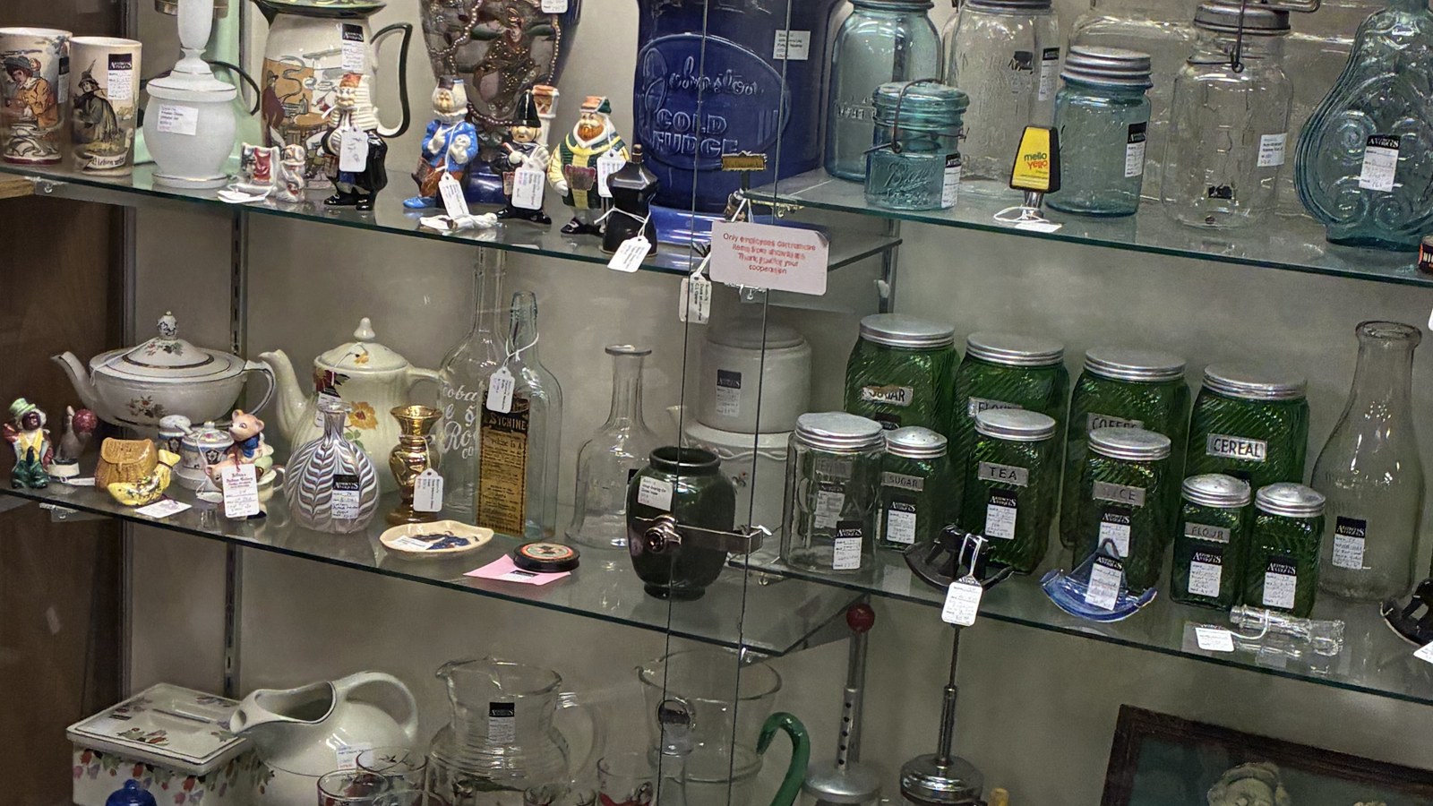 Kitchenware, glass jars, and vintage household pieces arranged inside a glass cabinet at Jeffrey's Antique Gallery