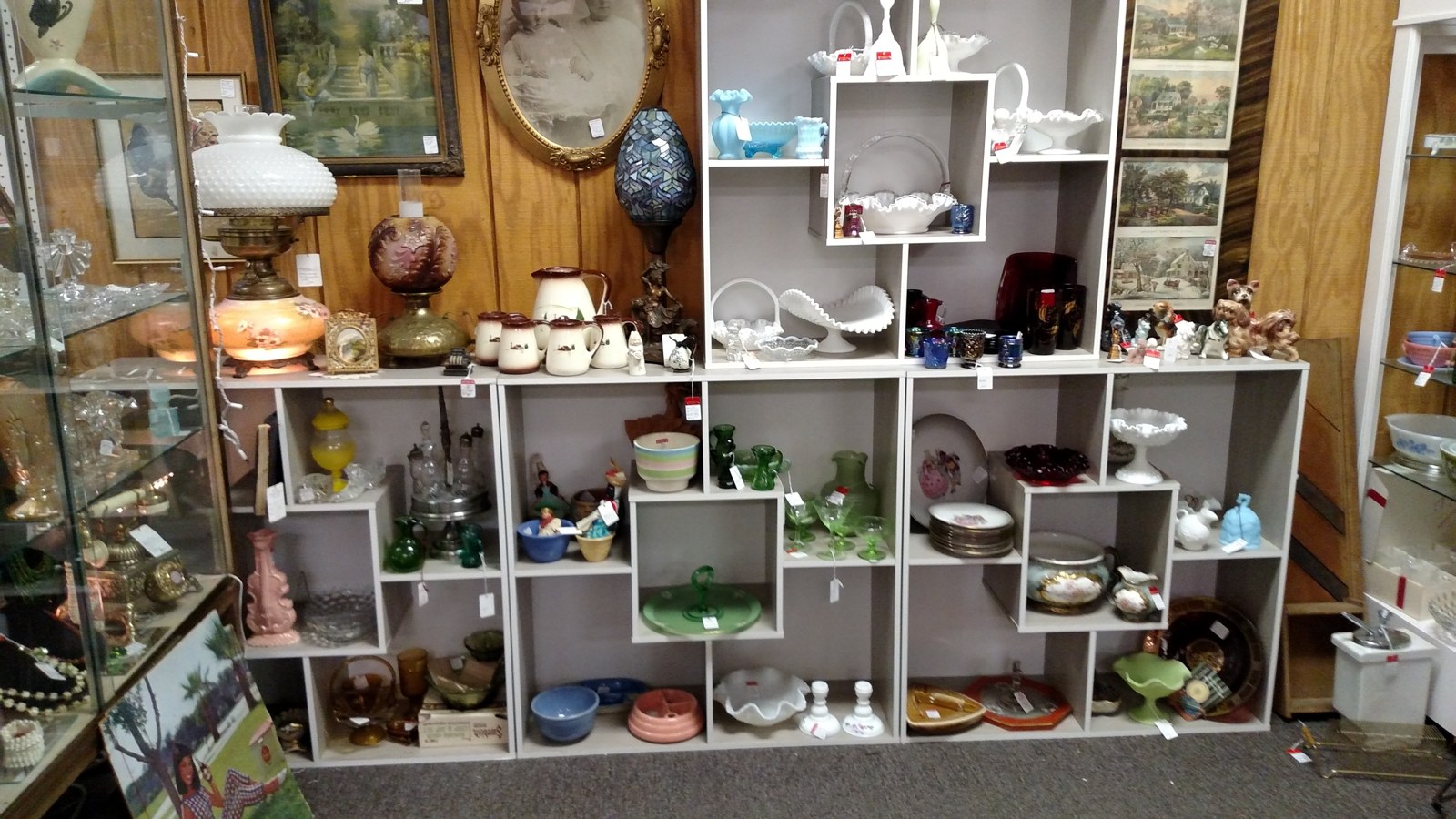 White milk glass, lamps, and framed art displayed in a decorative booth at Jeffrey's Antique Gallery