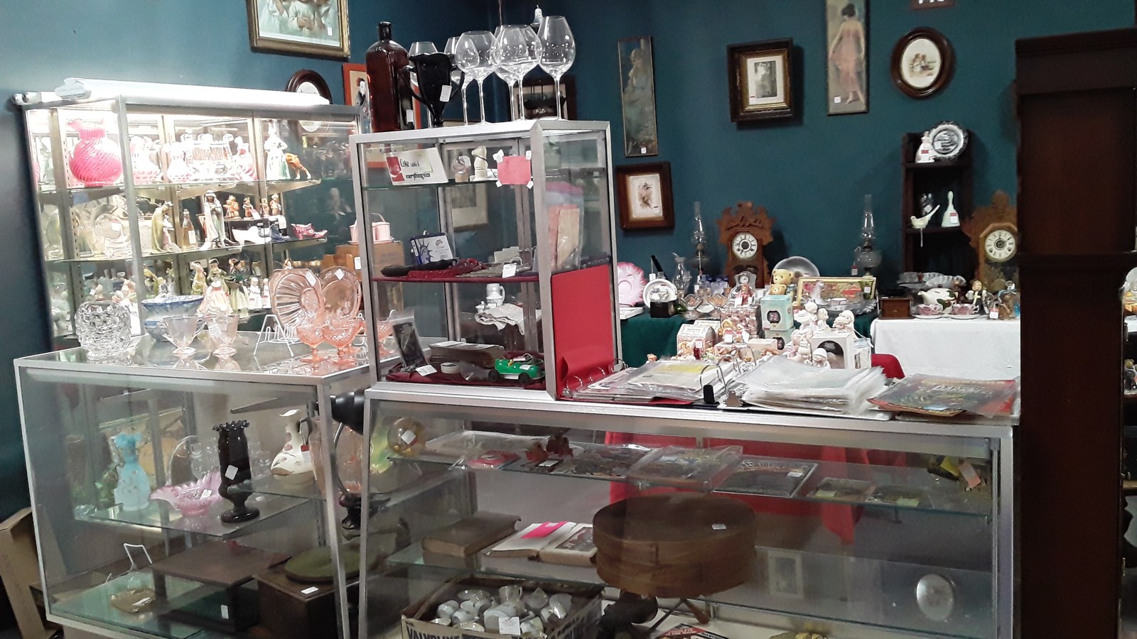 Curio room with clocks, figurines, and glass display cases inside Jeffrey's Antique Gallery