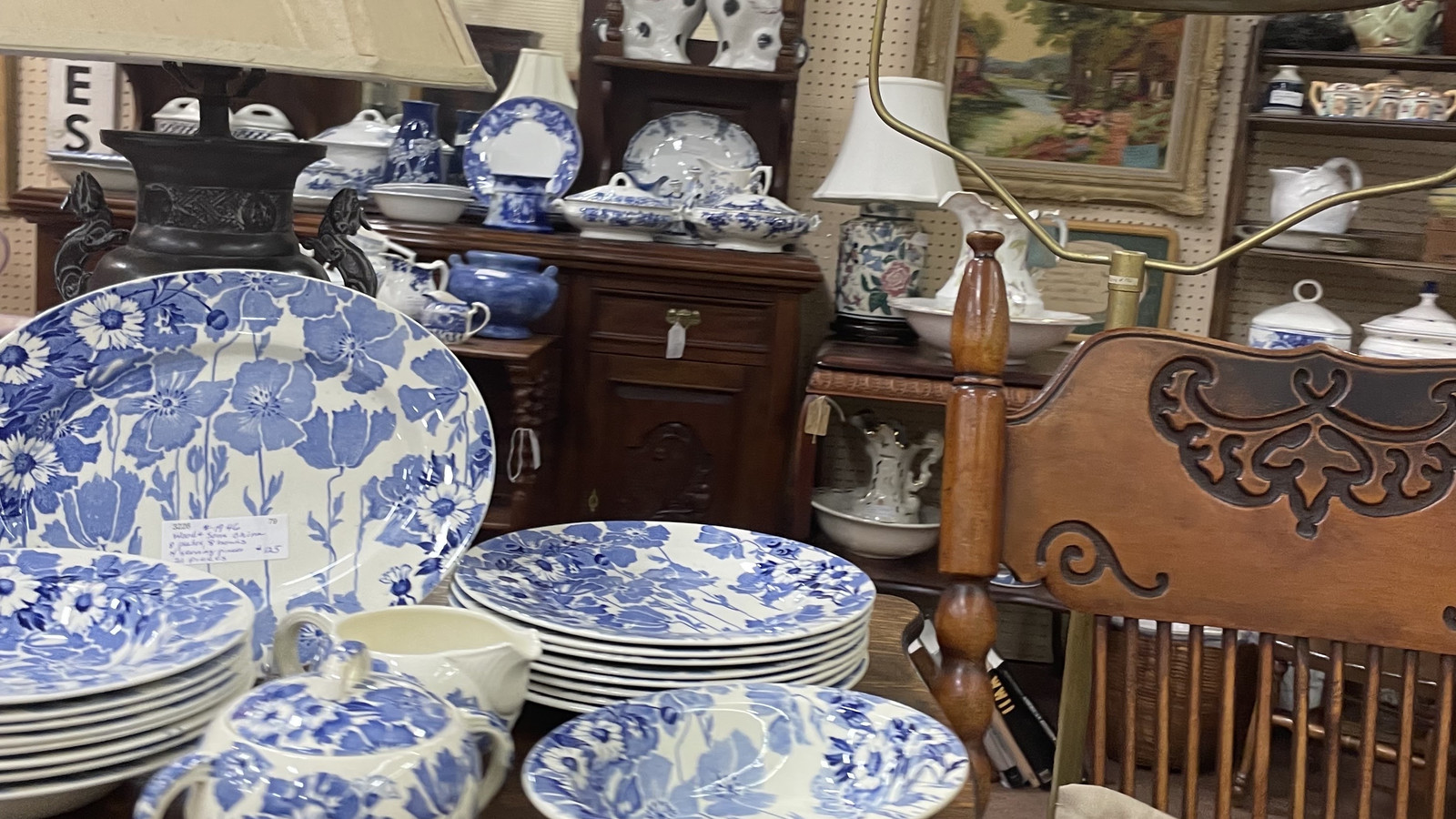 Blue transferware dishes, carved wood furniture, and a lamp grouped in a traditional display at Medina Antique Mall