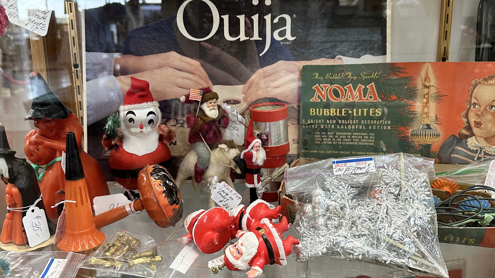 Ouija display case filled with playful novelties, holiday pieces, and small collectibles at Medina Antique Mall