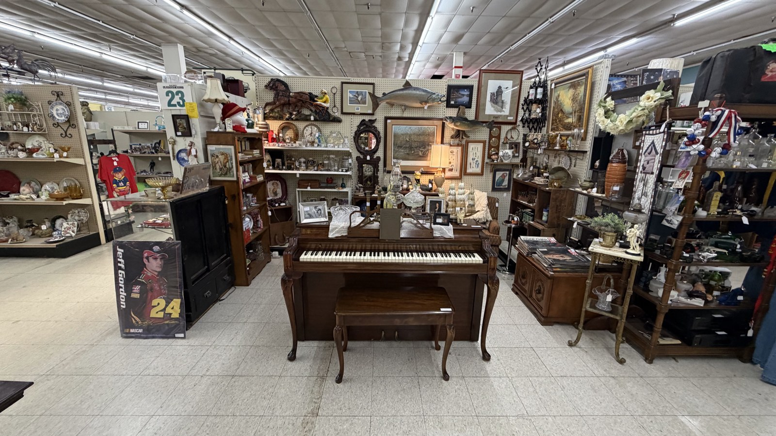 Piano, framed art, and a broad center aisle inside Maumee Antique Mall