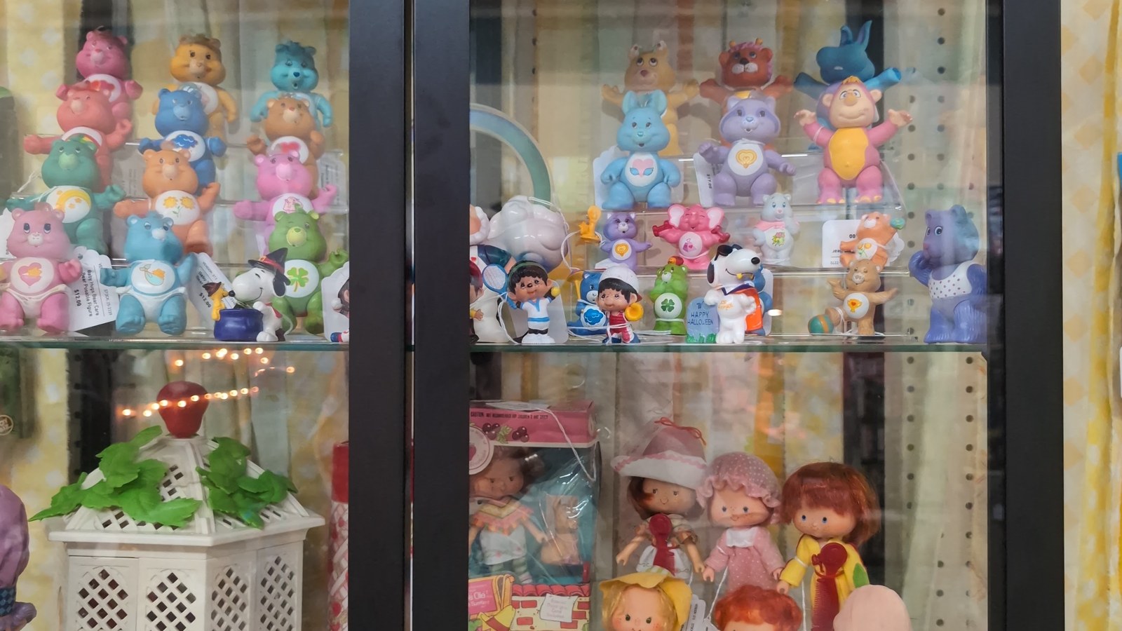 Colorful toy curio cabinet filled with bears, figurines, and dolls at Maumee Antique Mall