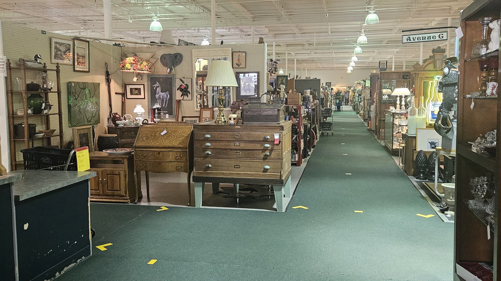 Wide main aisle lined with antiques, furniture, lamps, and display booths inside Heritage Square Antique Mall