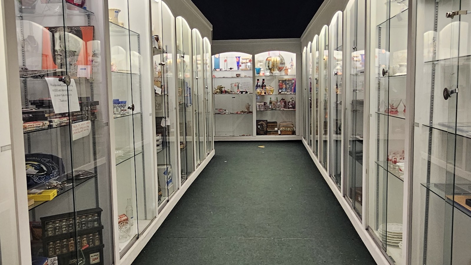 Long corridor of illuminated glass cases filled with collectibles inside Heritage Square Antique Mall