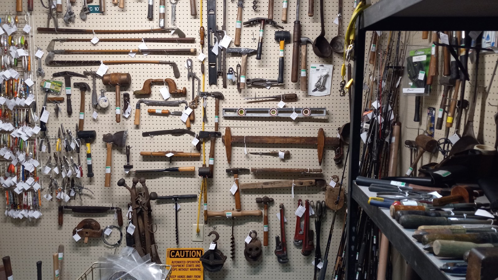 Wall display of antique hand tools, saws, hammers, and hardware at Heritage Square Antique Mall