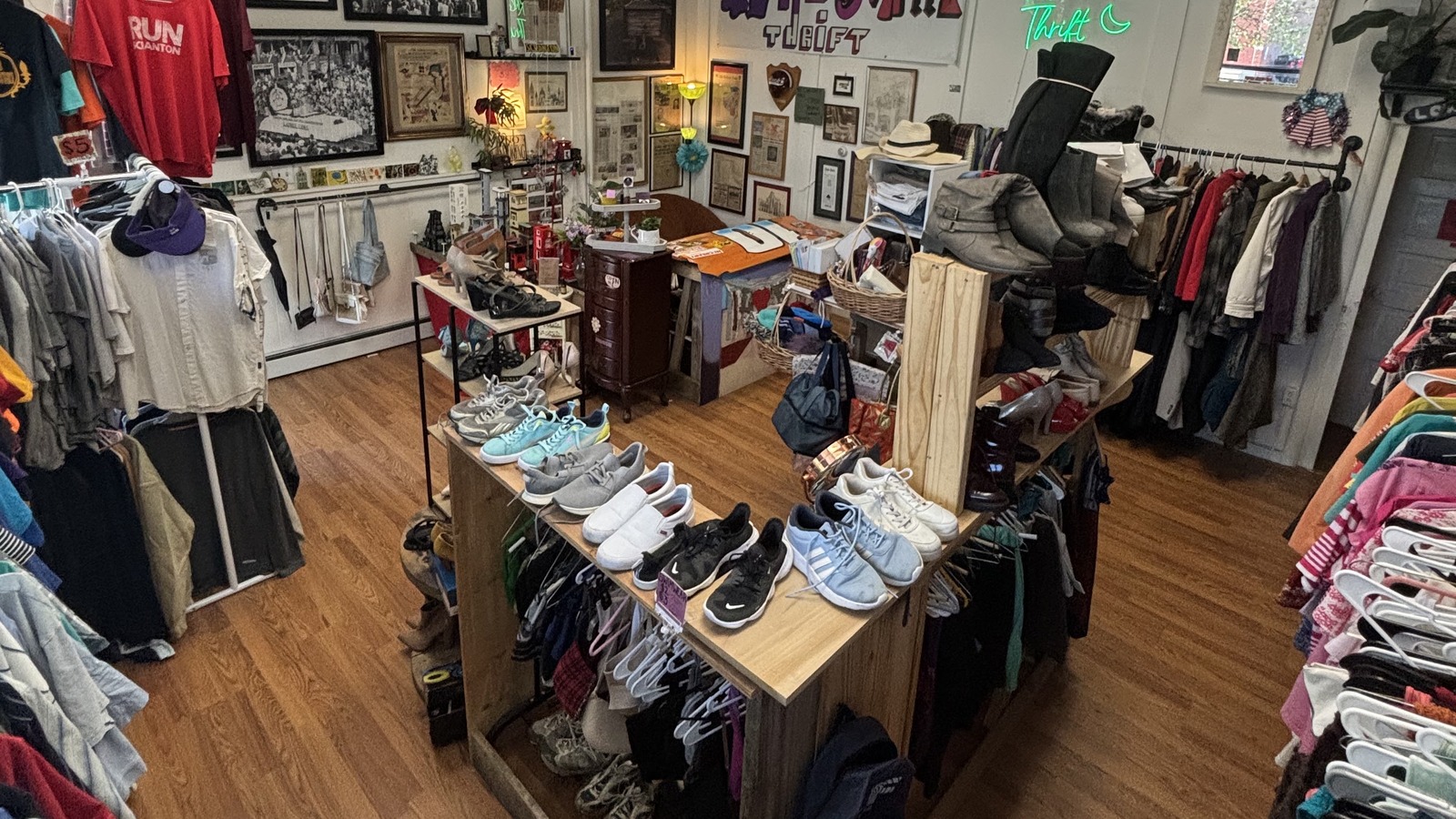 Main sales floor with shoes, clothing racks, framed art, and neon signage at Khlovan's Thrift