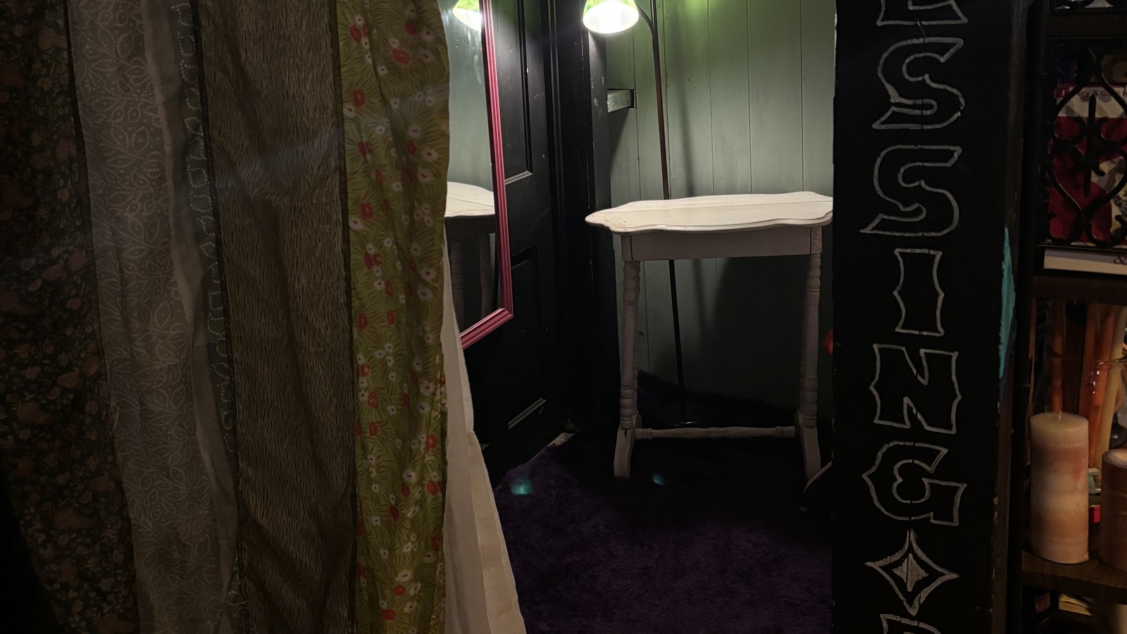 Curtained dressing room entry with mirror and sign at Khlovan's Thrift