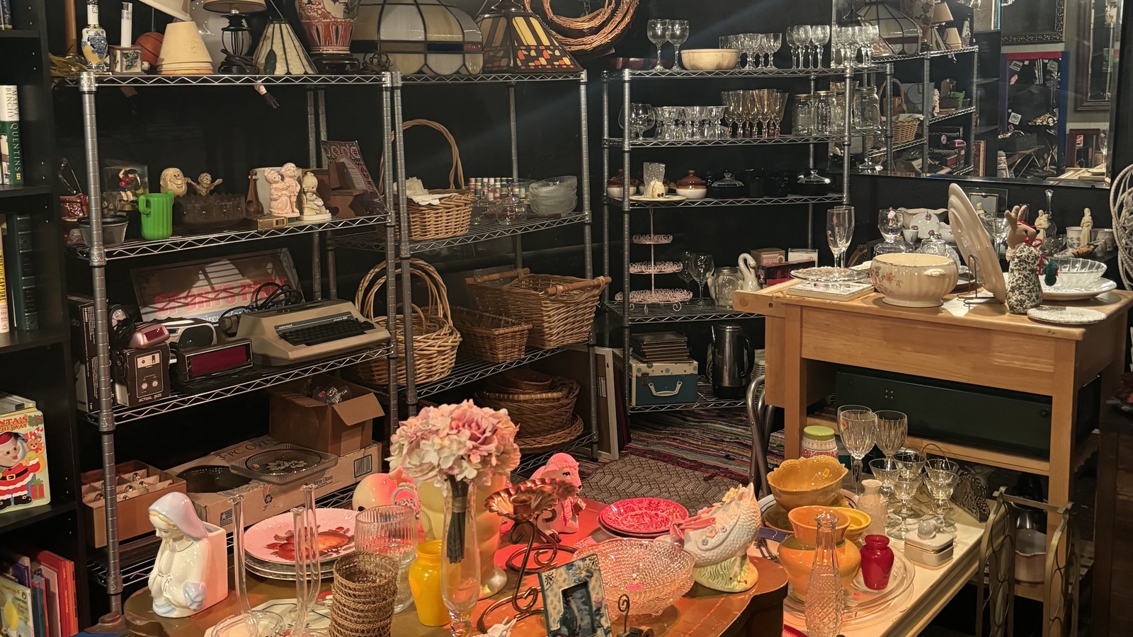 Basement housewares section with glassware, lamps, baskets, and serving pieces at Khlovan's Thrift
