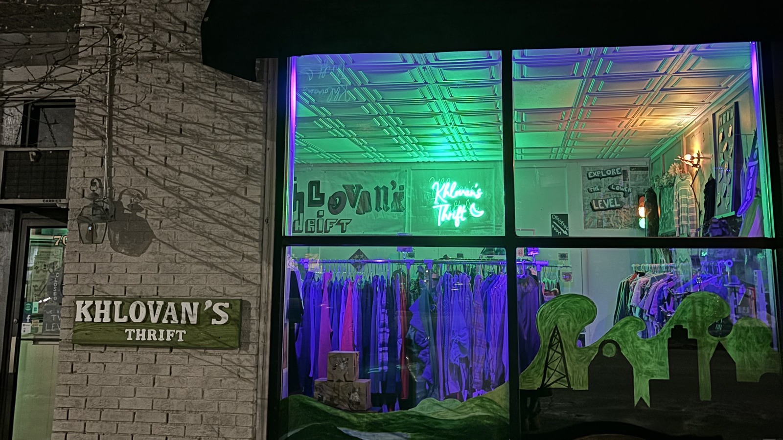 Nighttime window display glowing green and purple at Khlovan's Thrift in Scranton