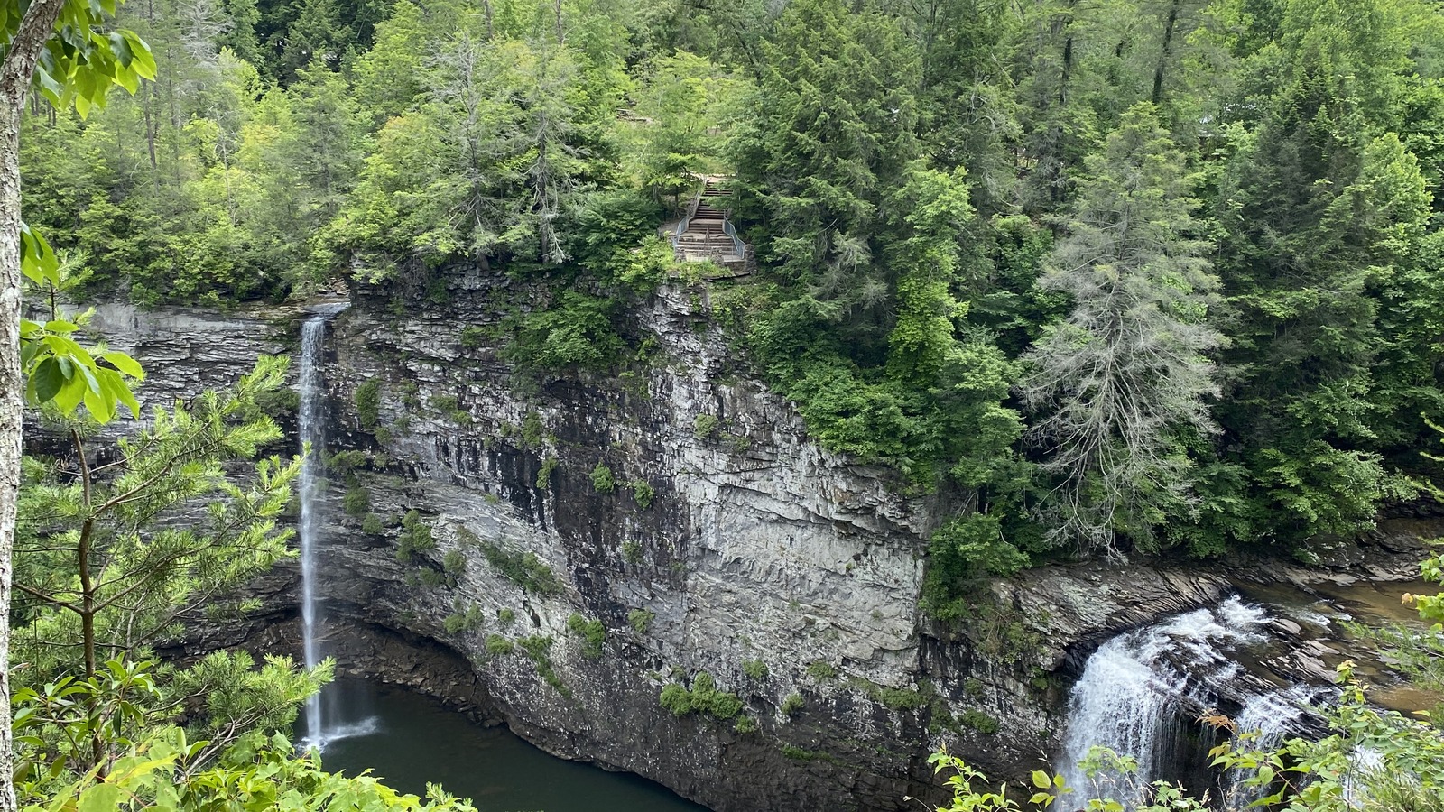 Two waterfalls stepping into a broad green gorge inside the park.