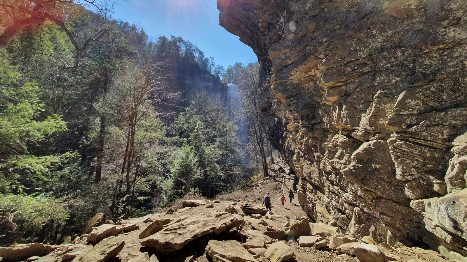 Boulder-strewn trail running beneath a towering sandstone wall.
