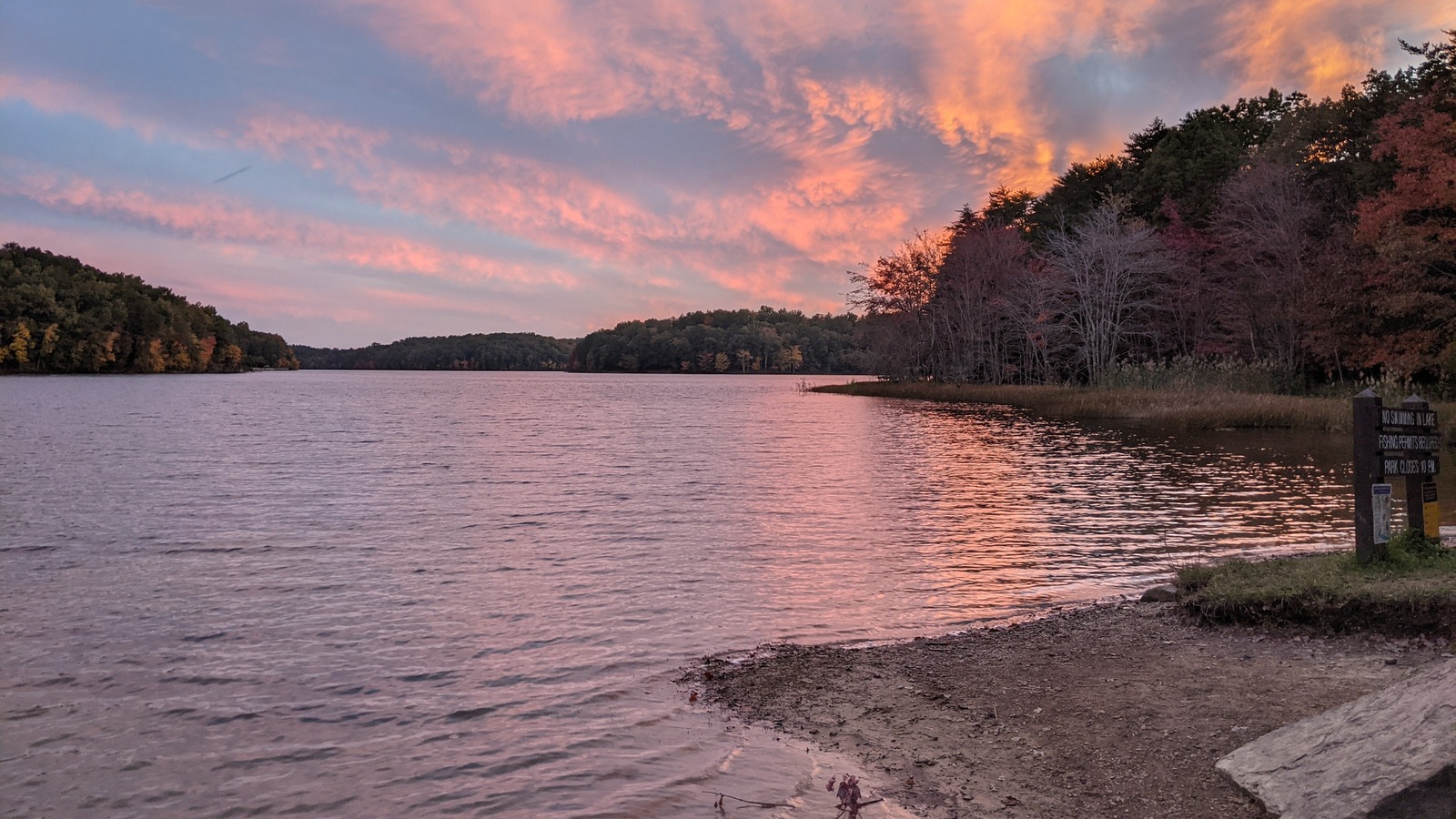 Pink sunset light reflecting across the park lake near the lodge shoreline.
