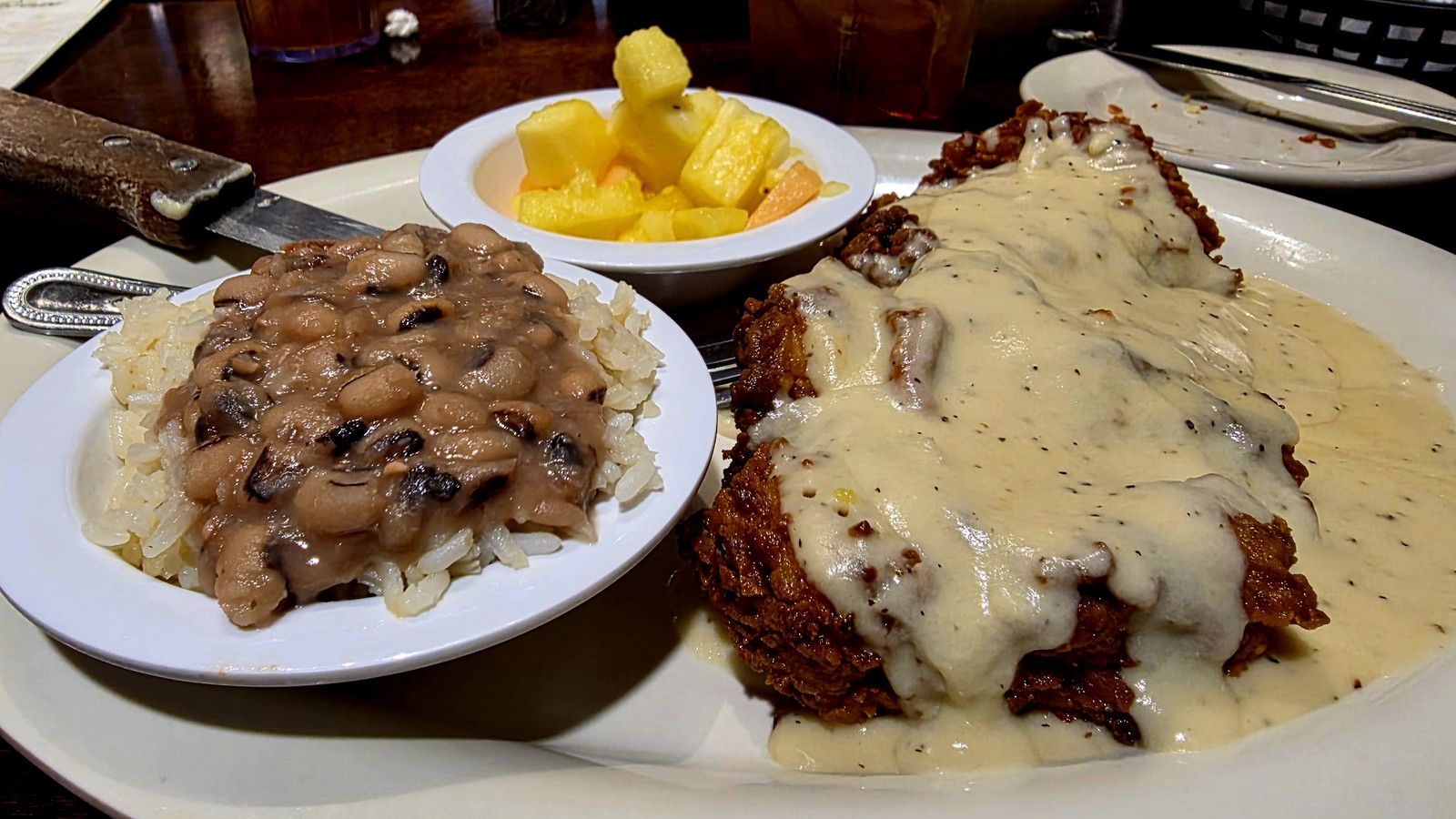 Chicken fried chicken covered in white pepper gravy with black-eyed peas and fruit