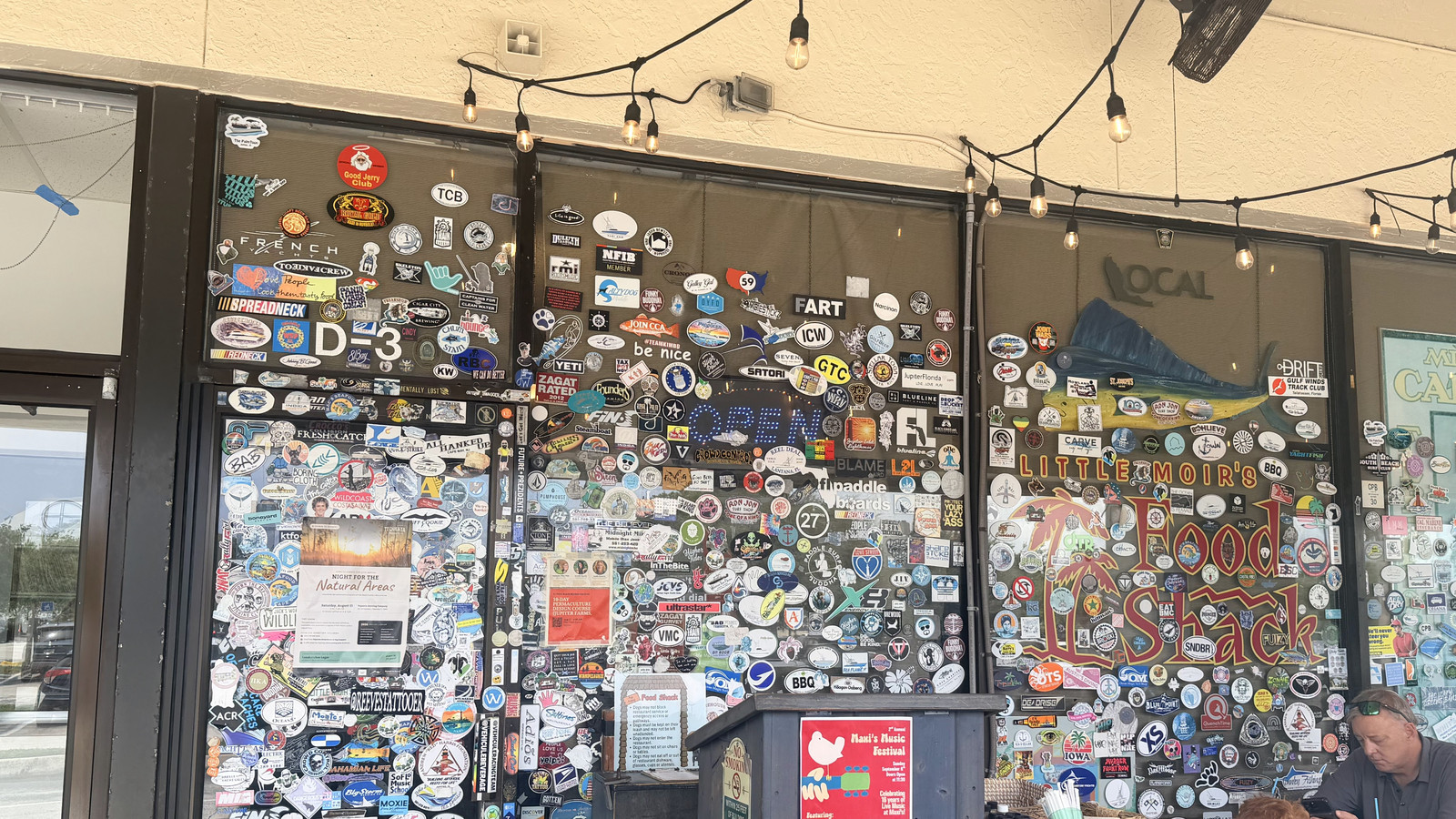 Sticker-covered front wall and marlin logo along the patio at Little Moir's Food Shack