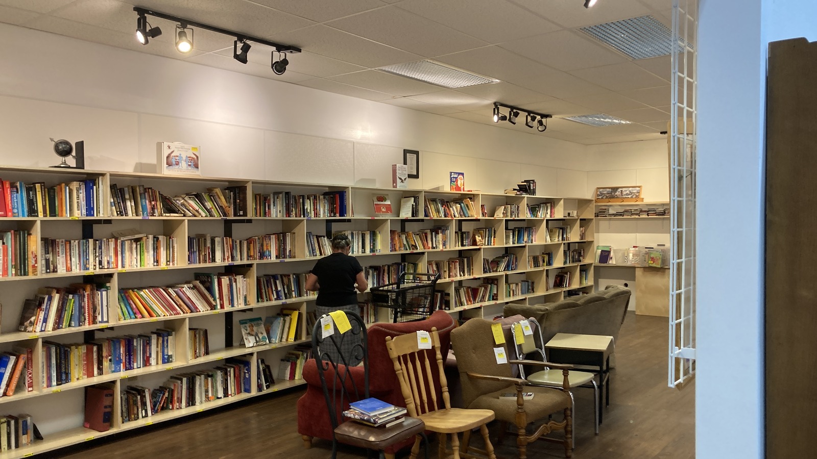 Long shelves of books and wooden chairs inside Mission Thrift Berlin