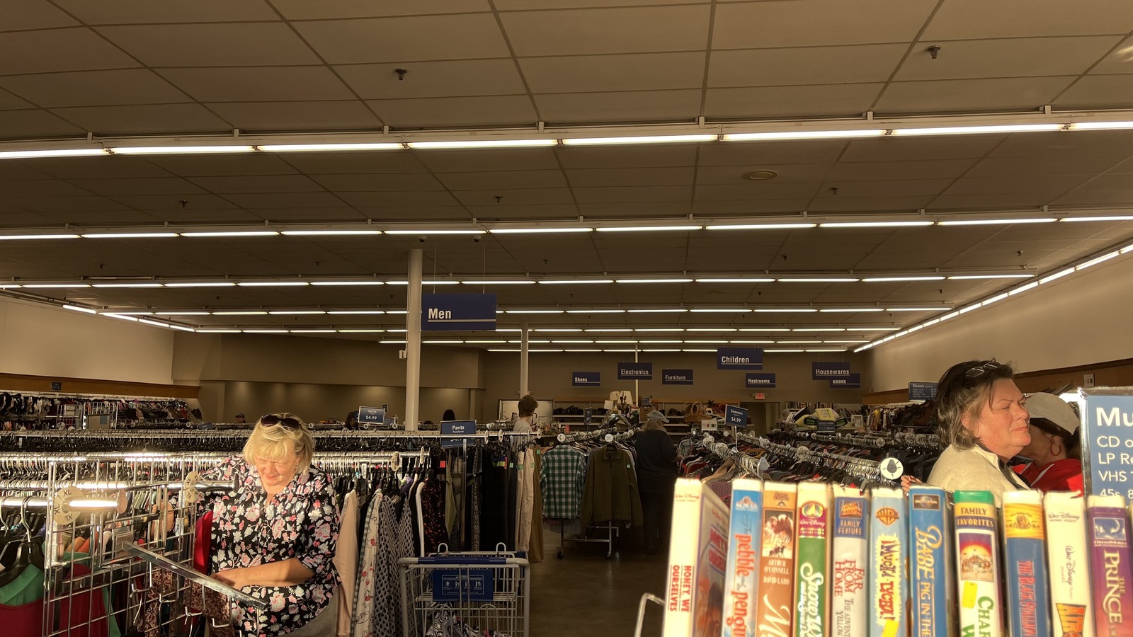 Long clothing racks and shelves of books inside the Morganton Goodwill on Bost Road