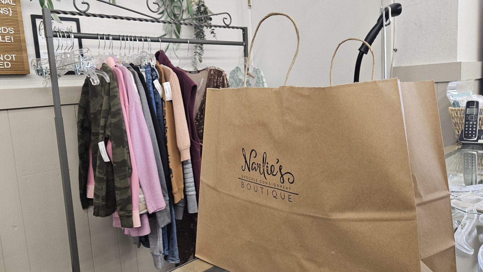 Clothing racks and a Narlie's Boutique shopping bag inside the consignment store