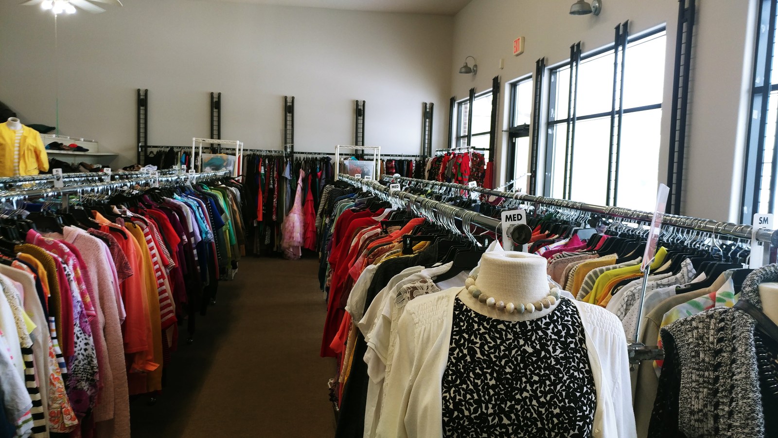 Bright clothing racks inside Someplace Safe Alexandria Thrift Store